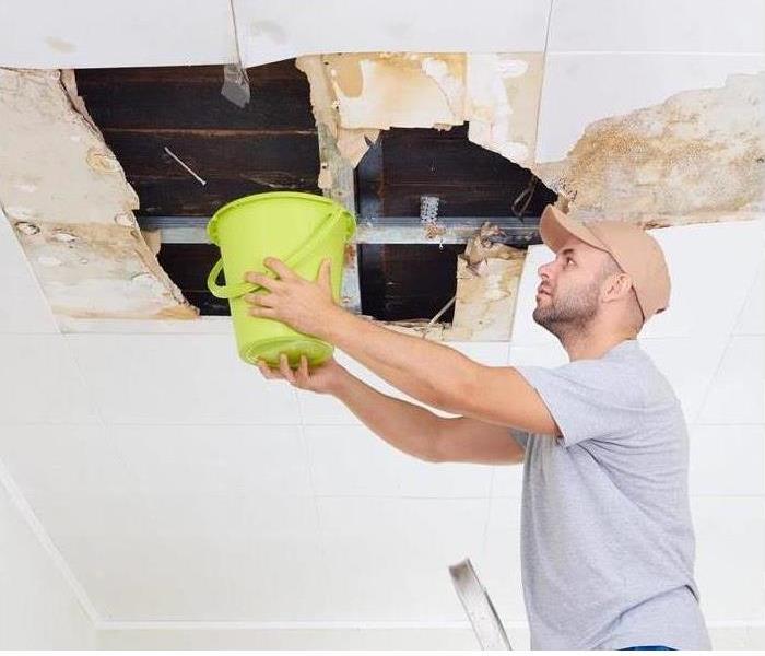 Guy holding a bucket on a leaking roof
